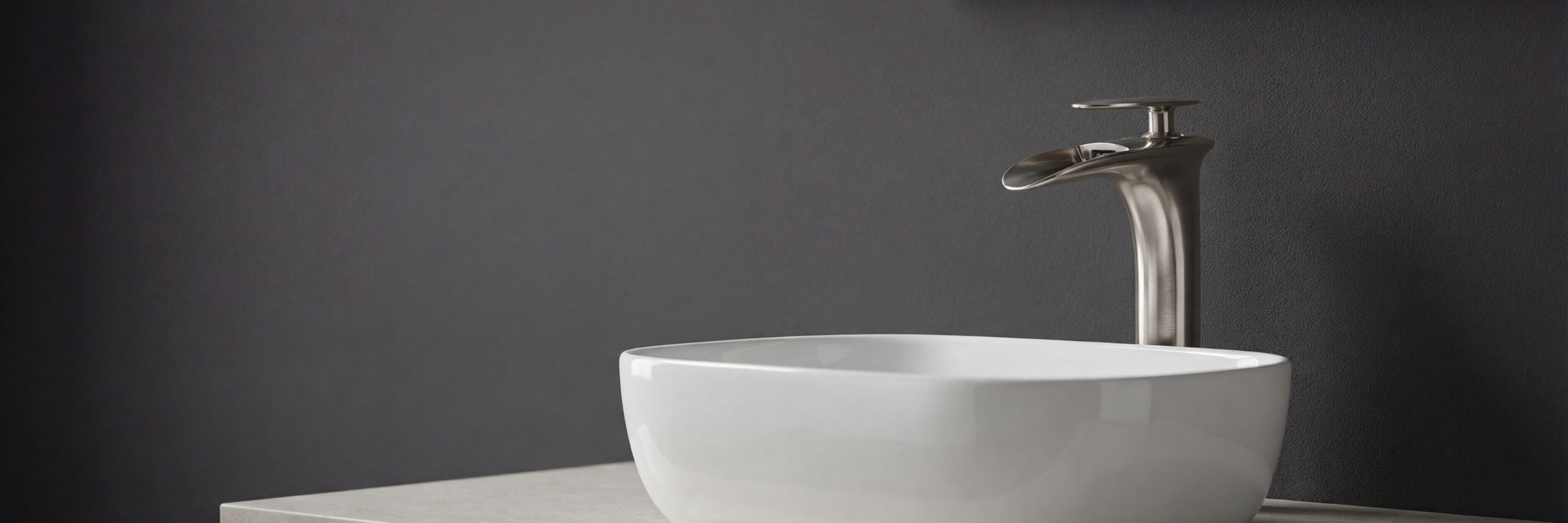 Modern Dunkel tall waterfall bathroom faucet in brushed nickel, featuring a single-hole and single-handle design over a white vessel sink against a dark gray wall.