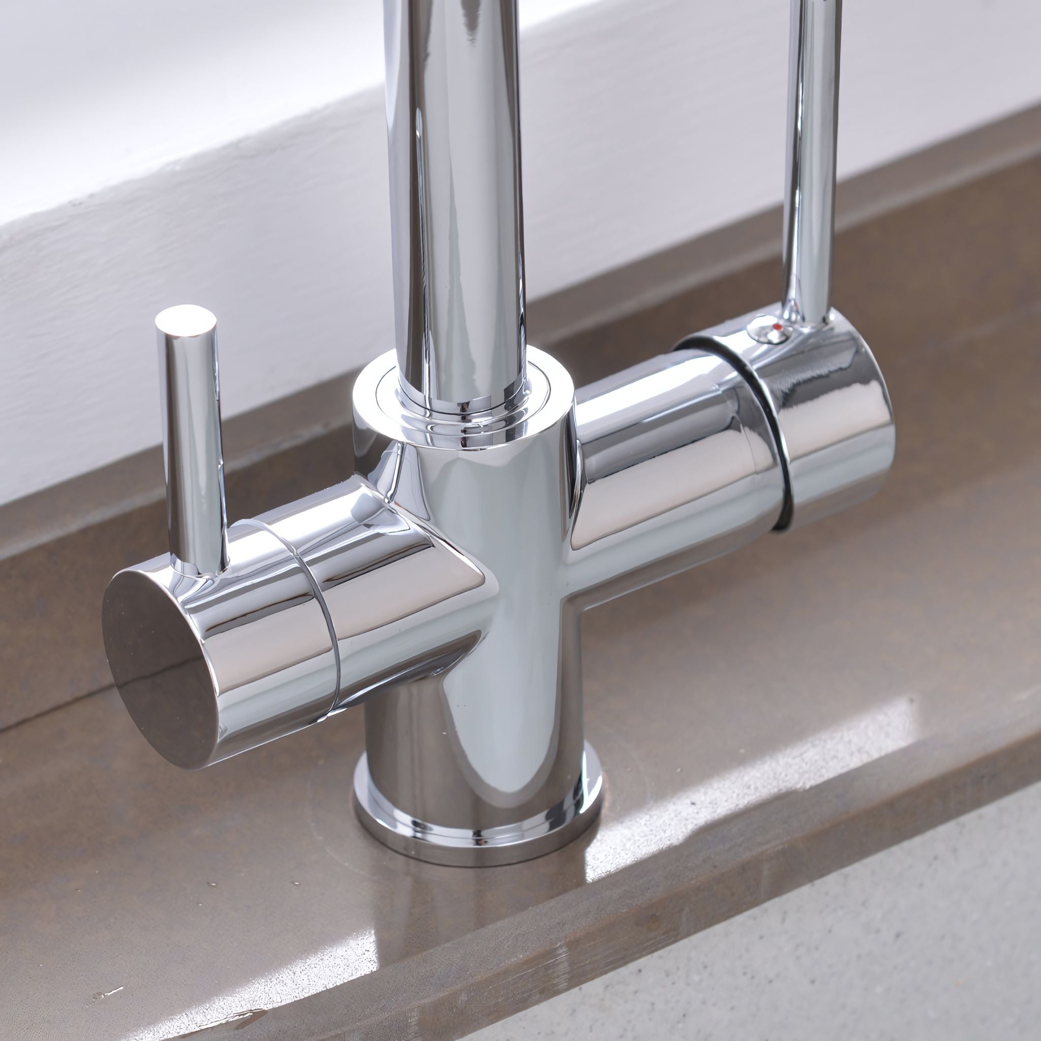 A modern chrome single-handle kitchen faucet with a tall spout, shown installed on a beige countertop. #color_chrome