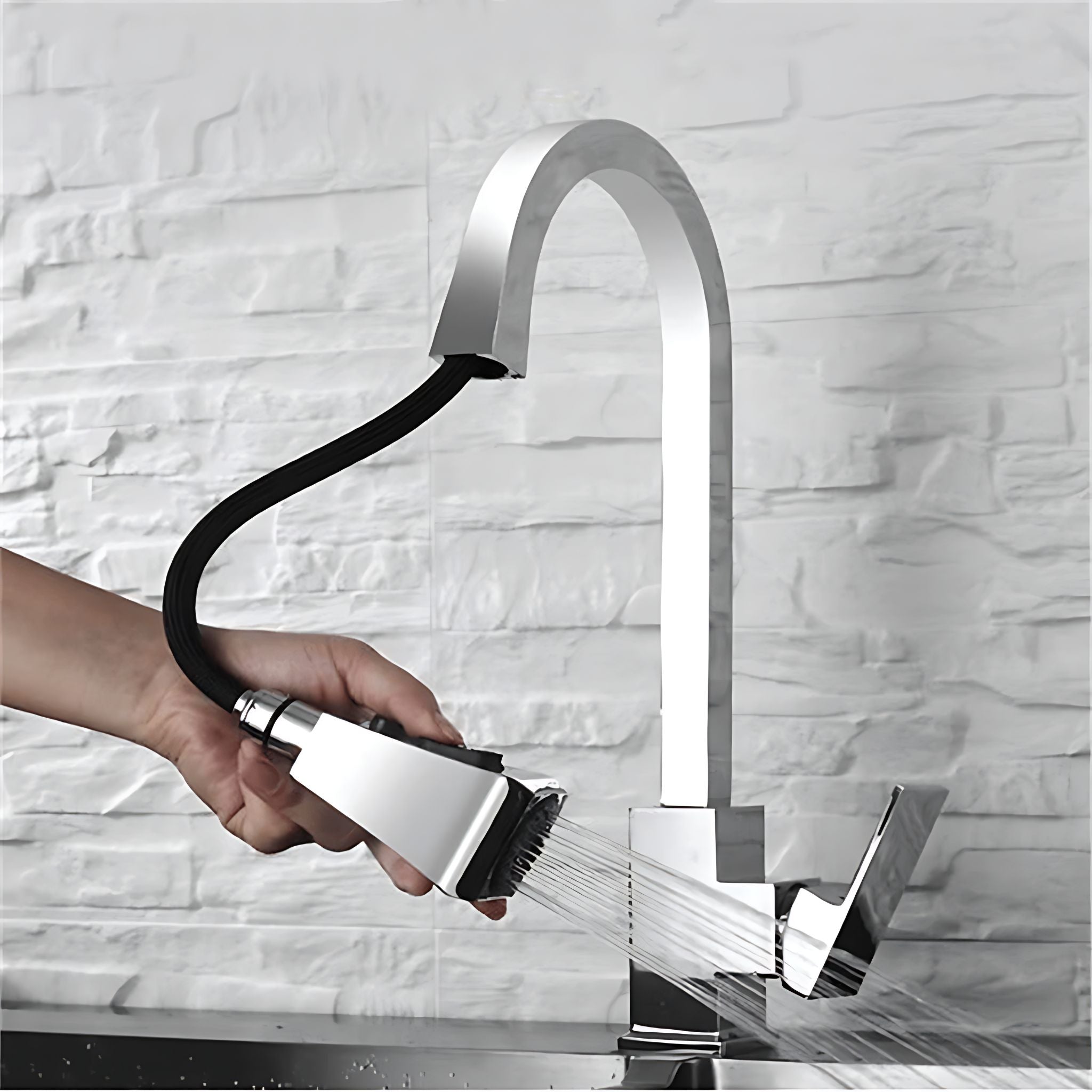 A modern high-arc chrome faucet with a flexible black hose and pull-out spray head, shown with water running while a hand holds the sprayer in front of a white textured brick wall. #color_chrome