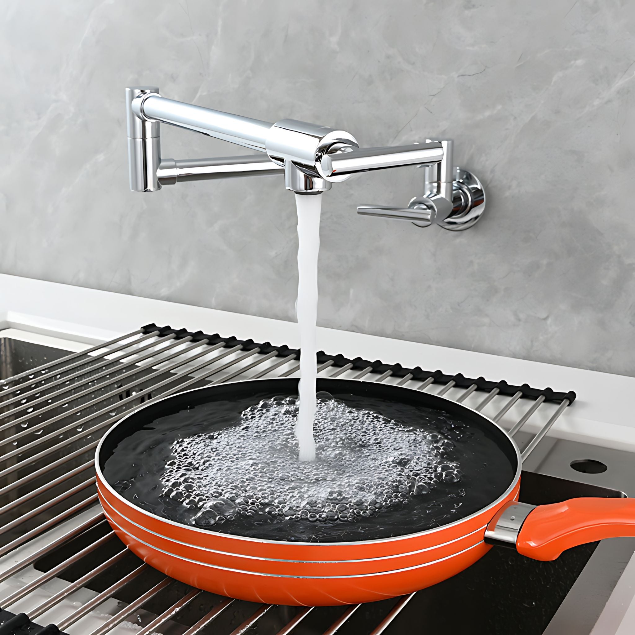 A bright orange frying pan sits in a sink under a wall-mounted chrome faucet with water running into it, against a gray tiled backsplash. #color_chrome