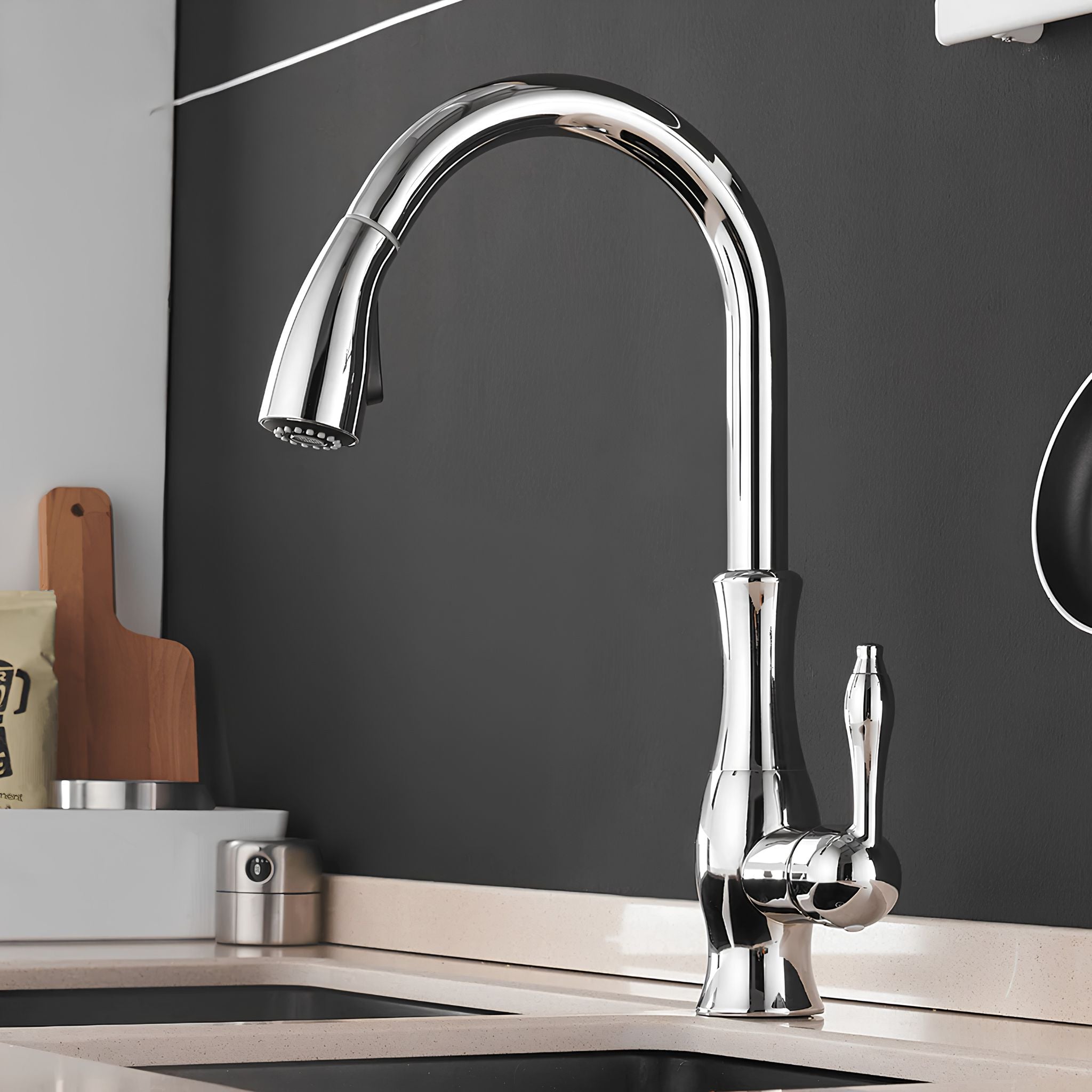 A polished chrome high-arc pull-down kitchen faucet with a single lever handle, installed on a light beige countertop against a dark charcoal wall. #color_chrome