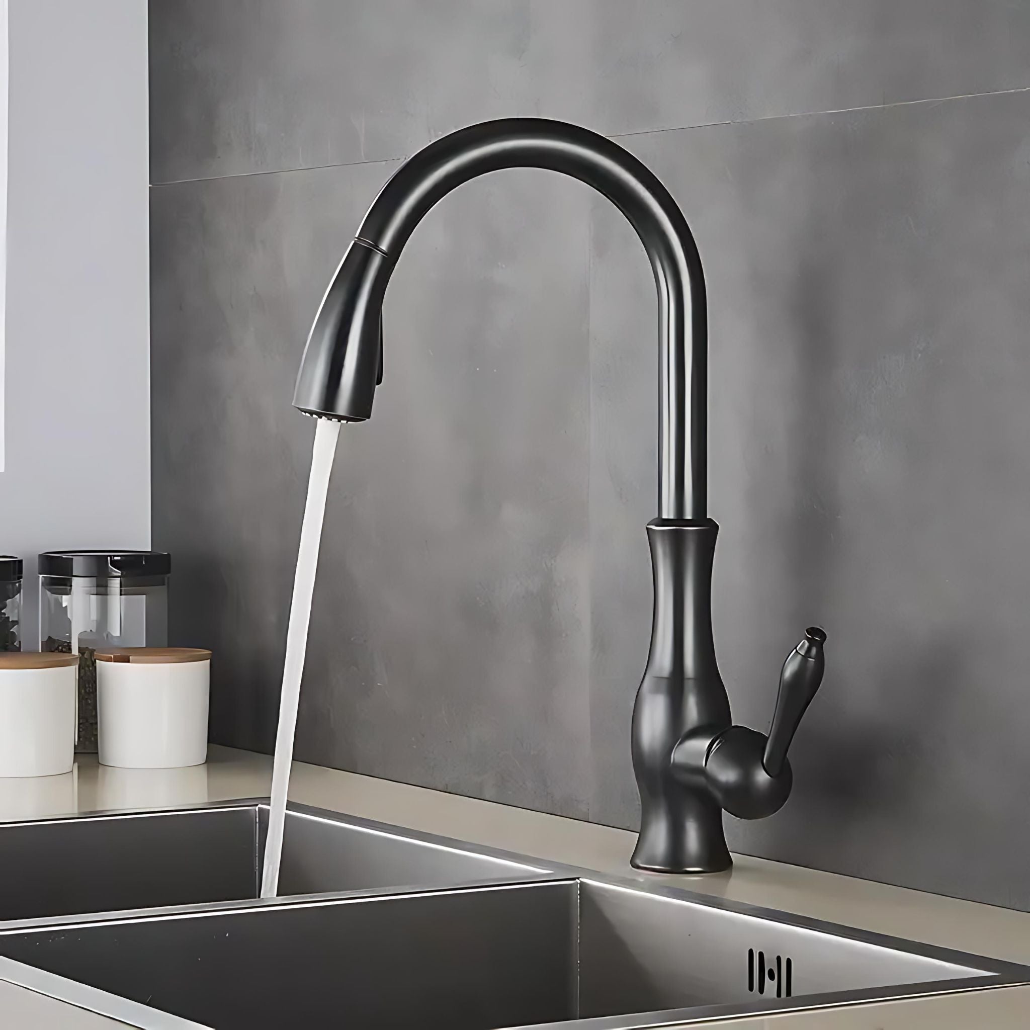 A matte black high-arc pull-down kitchen faucet with running water, installed in a double-basin stainless steel sink against a gray tiled backsplash. #color_matte black