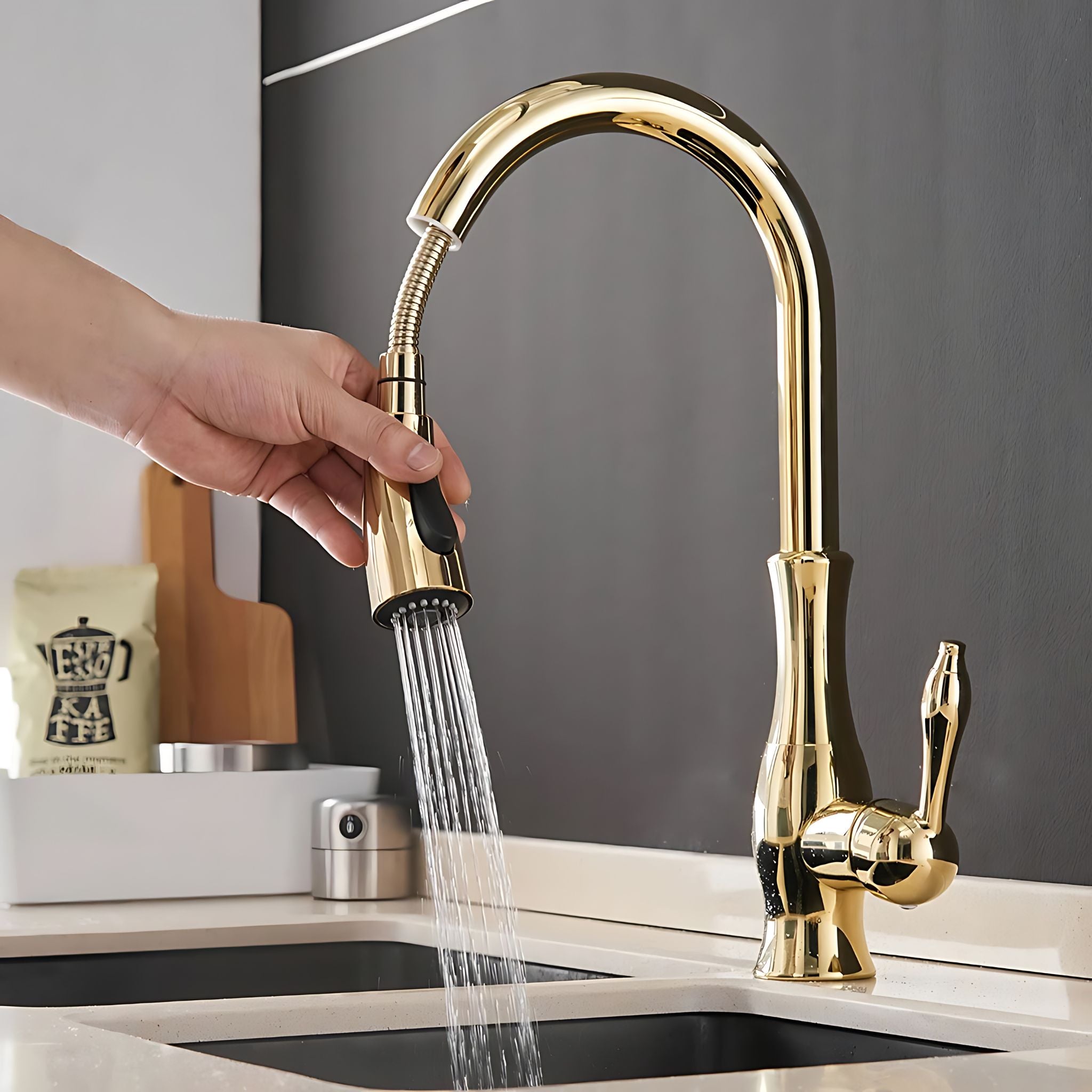 A high-arc pull-down kitchen faucet in polished gold finish, shown with a hand turning on the spray head and water flowing into a sink. The faucet is installed on a light countertop against a dark gray backsplash. #color_gold