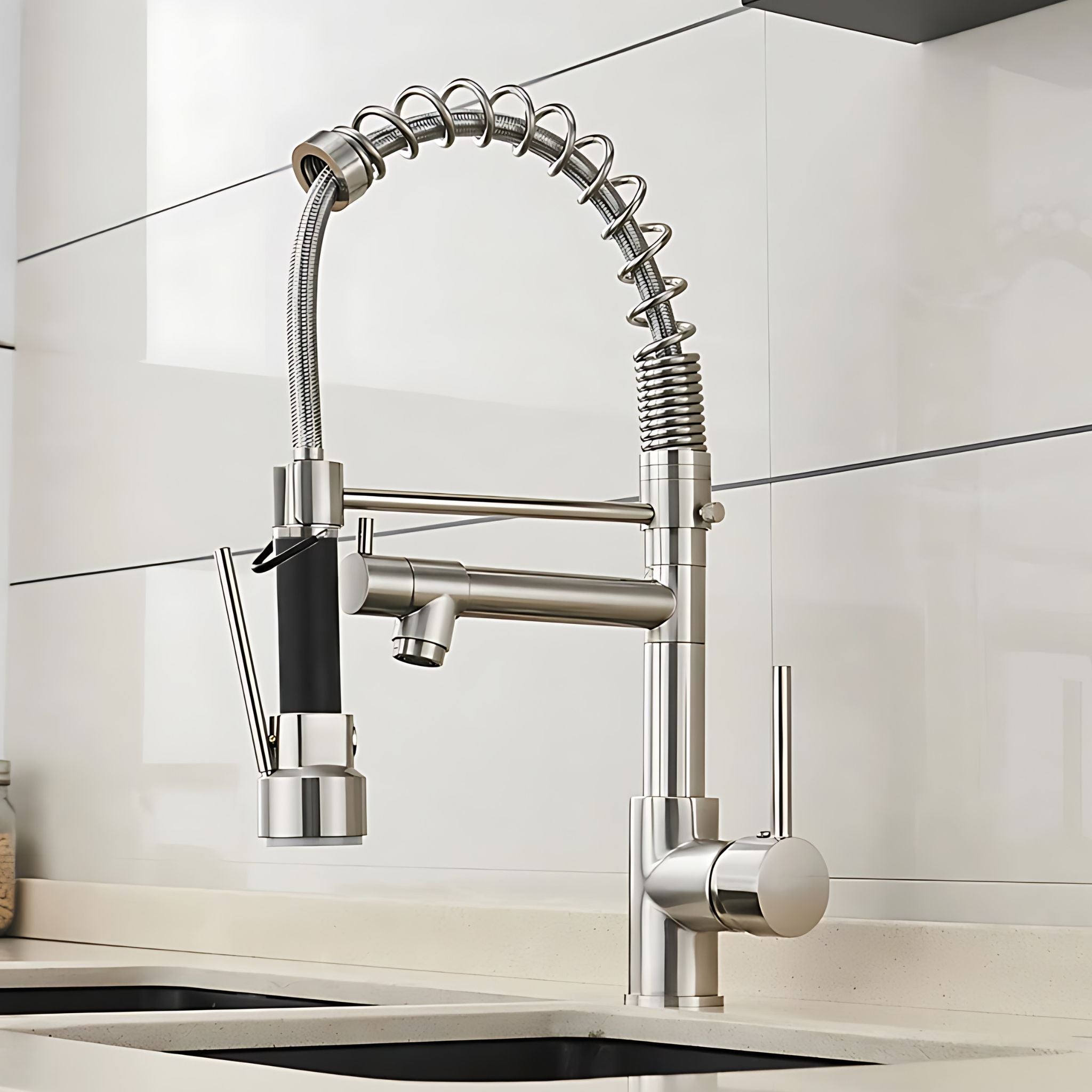A modern stainless steel kitchen faucet with a flexible gooseneck sprayer and side-mounted filter, installed on a sink against a white tiled backsplash. #color_brushed nickel