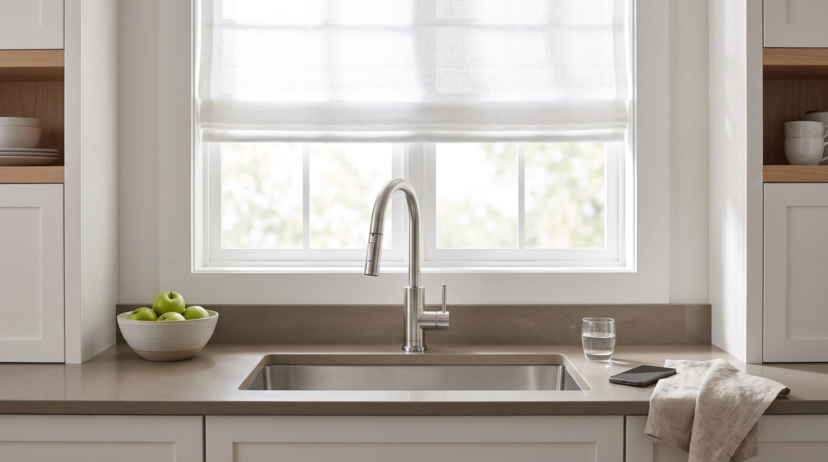 Brushed nickel Imperium kitchen faucet at a single sink under a bright window, a phone resting face down on the counter