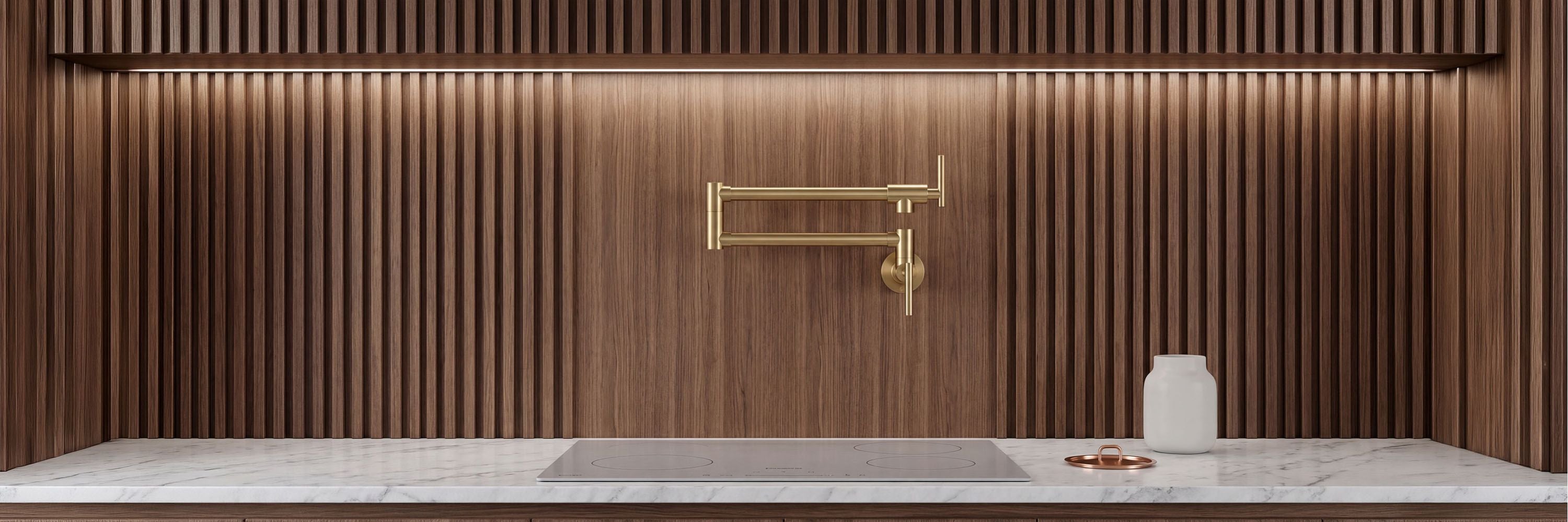 Brushed gold Gertner wall mount pot filler faucet filling a metal pot on a modern kitchen stove.