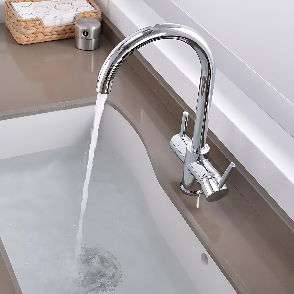 A modern chrome single-handle kitchen faucet with a high-arc spout, shown running water into a white sink. The faucet is mounted on a brown countertop next to a white sink basin. #color_chrome