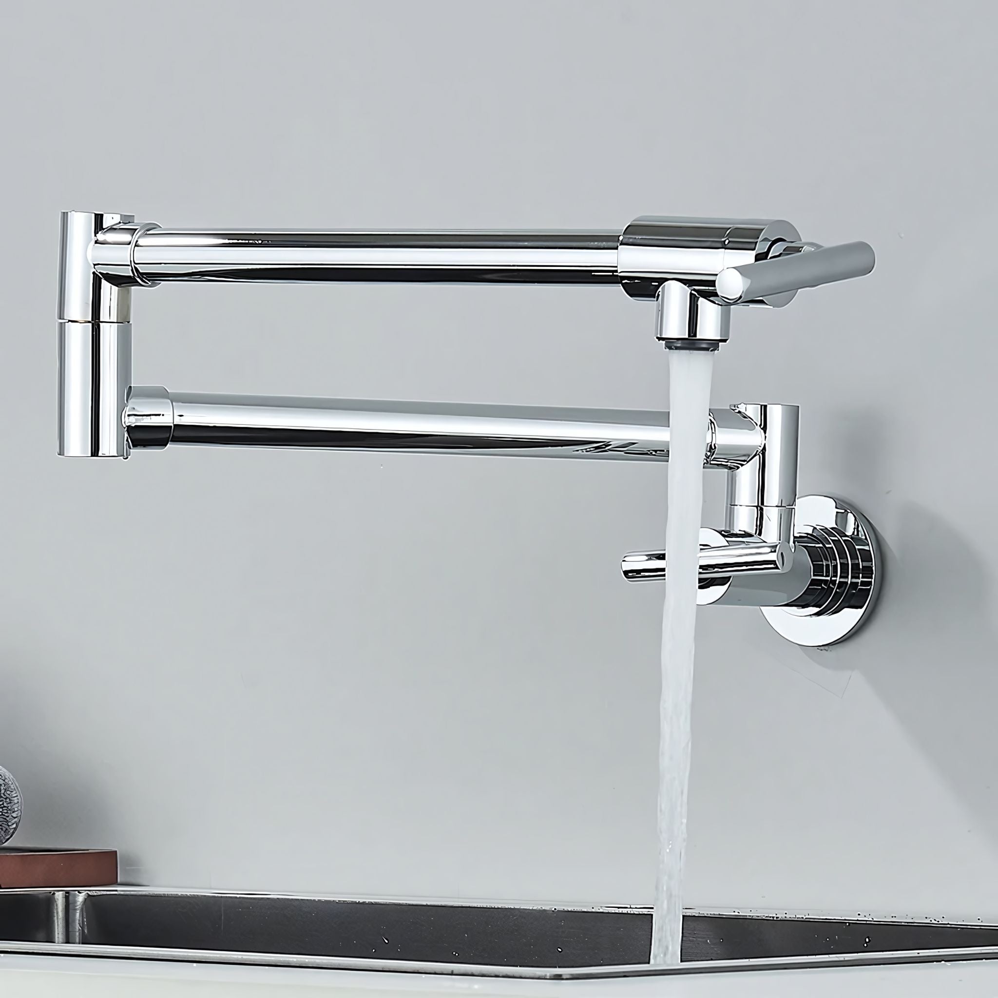 A modern wall-mounted kitchen faucet with a polished chrome finish, featuring two horizontal spout bars and a vertical main spout with running water, installed above a dark sink against a light gray wall. #color_chrome