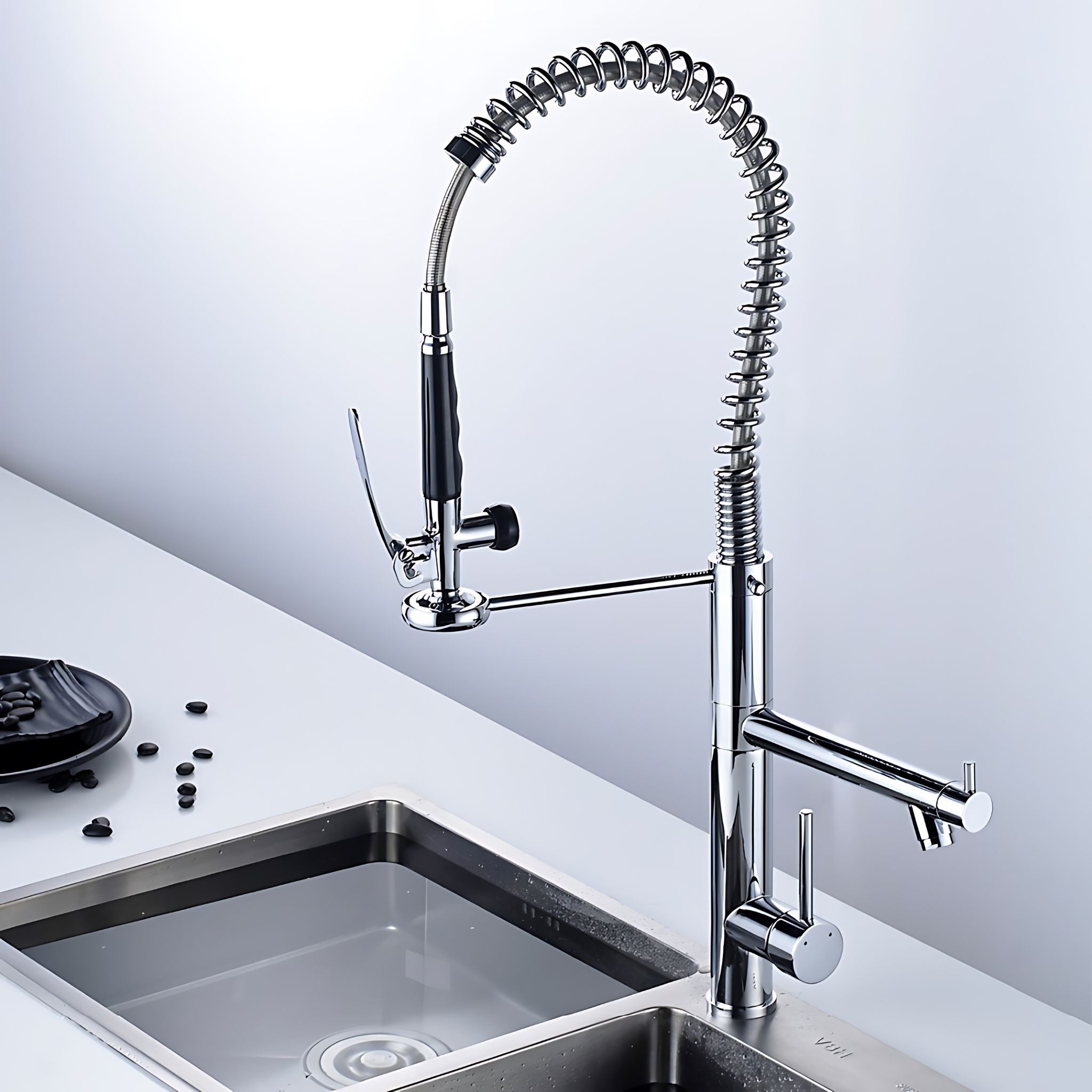 A modern high-arc chrome pull-down kitchen faucet with a side-mounted spray head and a single-handle control, installed over a stainless steel sink on a white countertop. #color_chrome