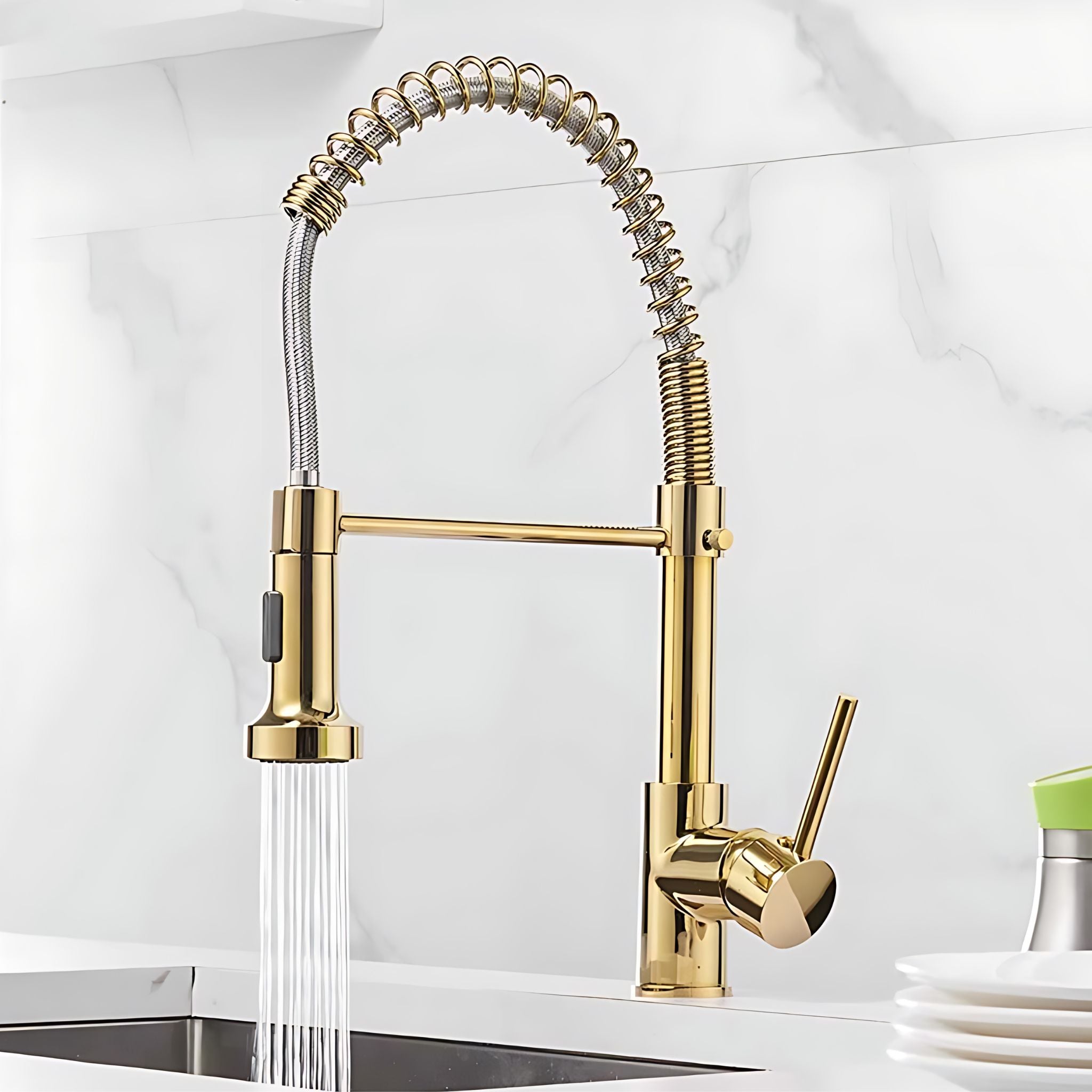 Gold pull-down kitchen faucet with a flexible spring hose and water running from the spray head, installed over a sink with a white marble backsplash. #color_gold