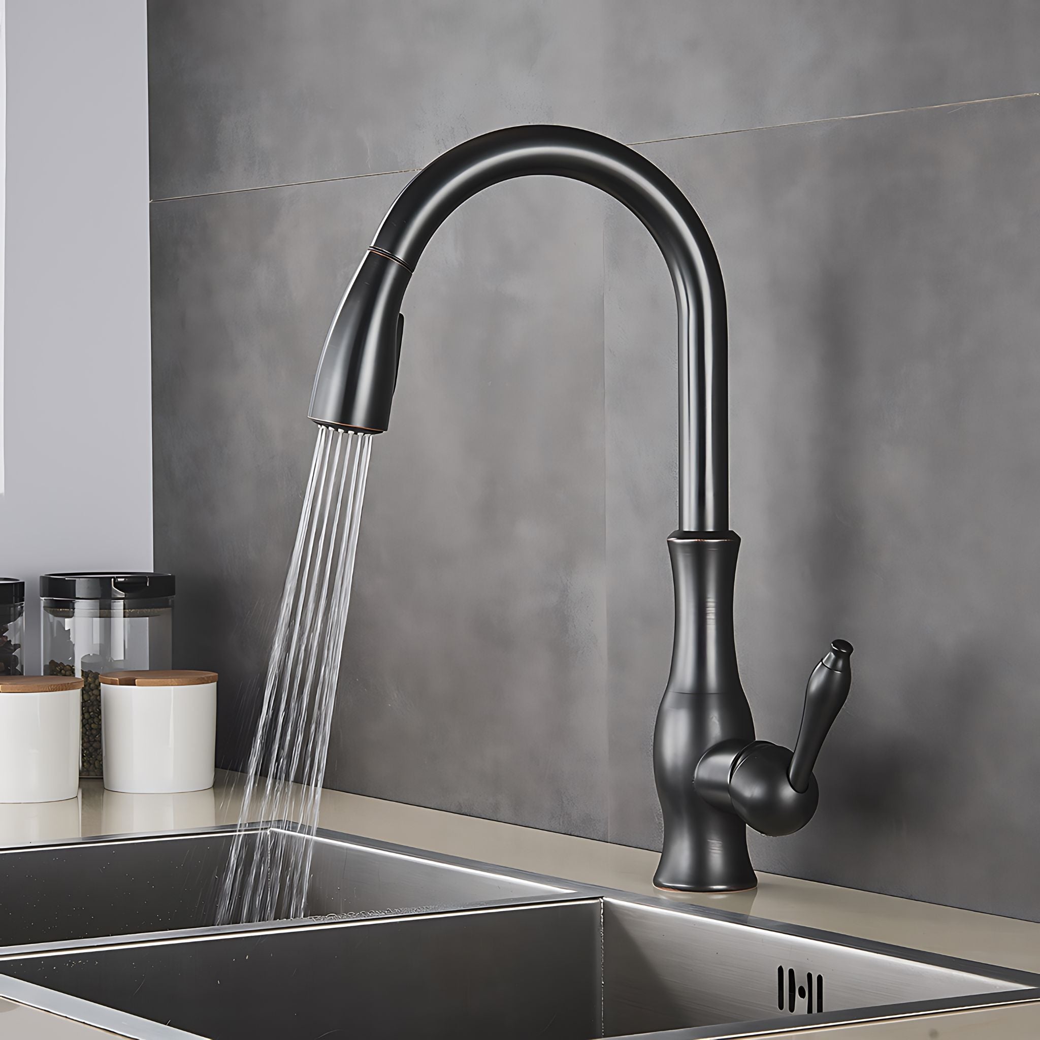A matte black pull-down kitchen faucet with water running from the spout, installed over a stainless steel double basin sink against a gray tiled backsplash. #color_matte black