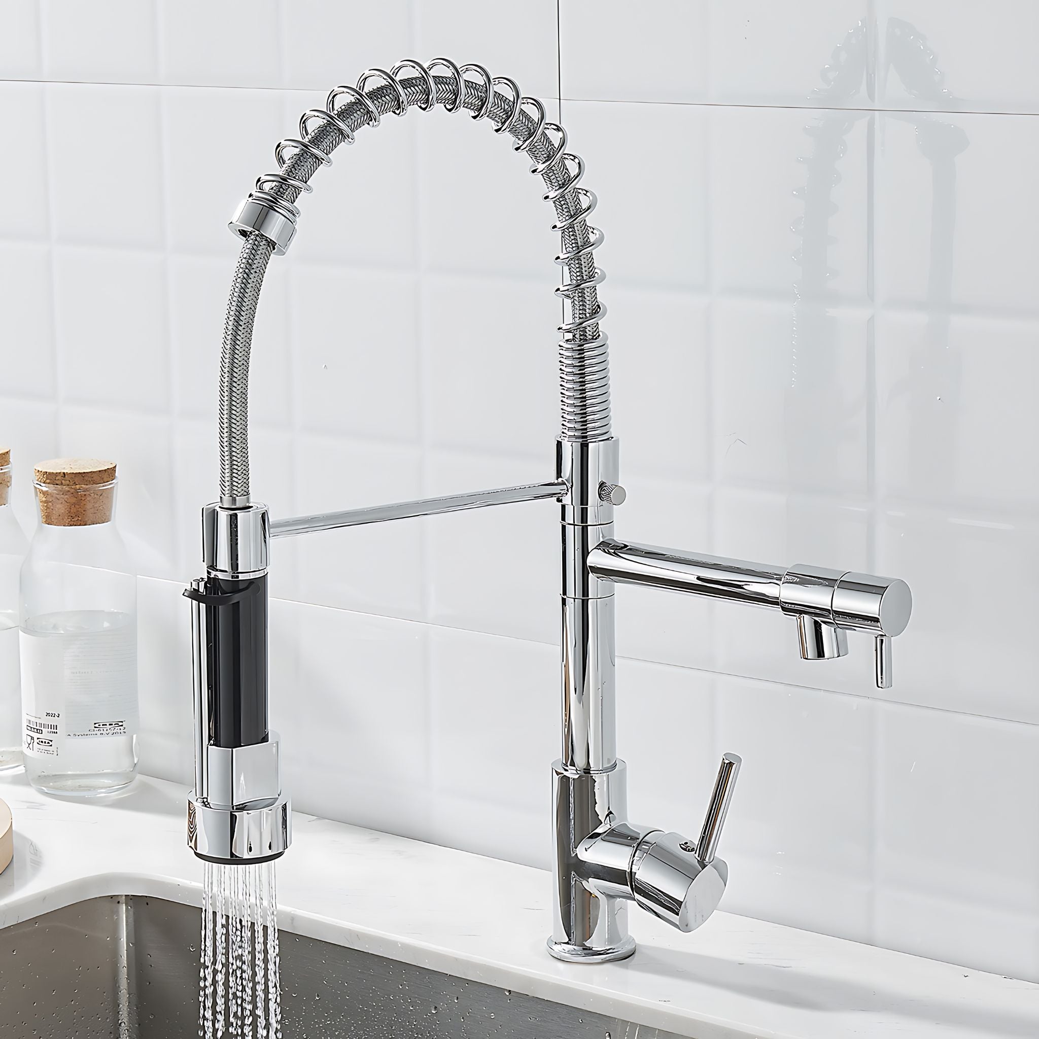 Chrome kitchen faucet with a pull-down sprayer on a white tiled wall background. #color_chrome