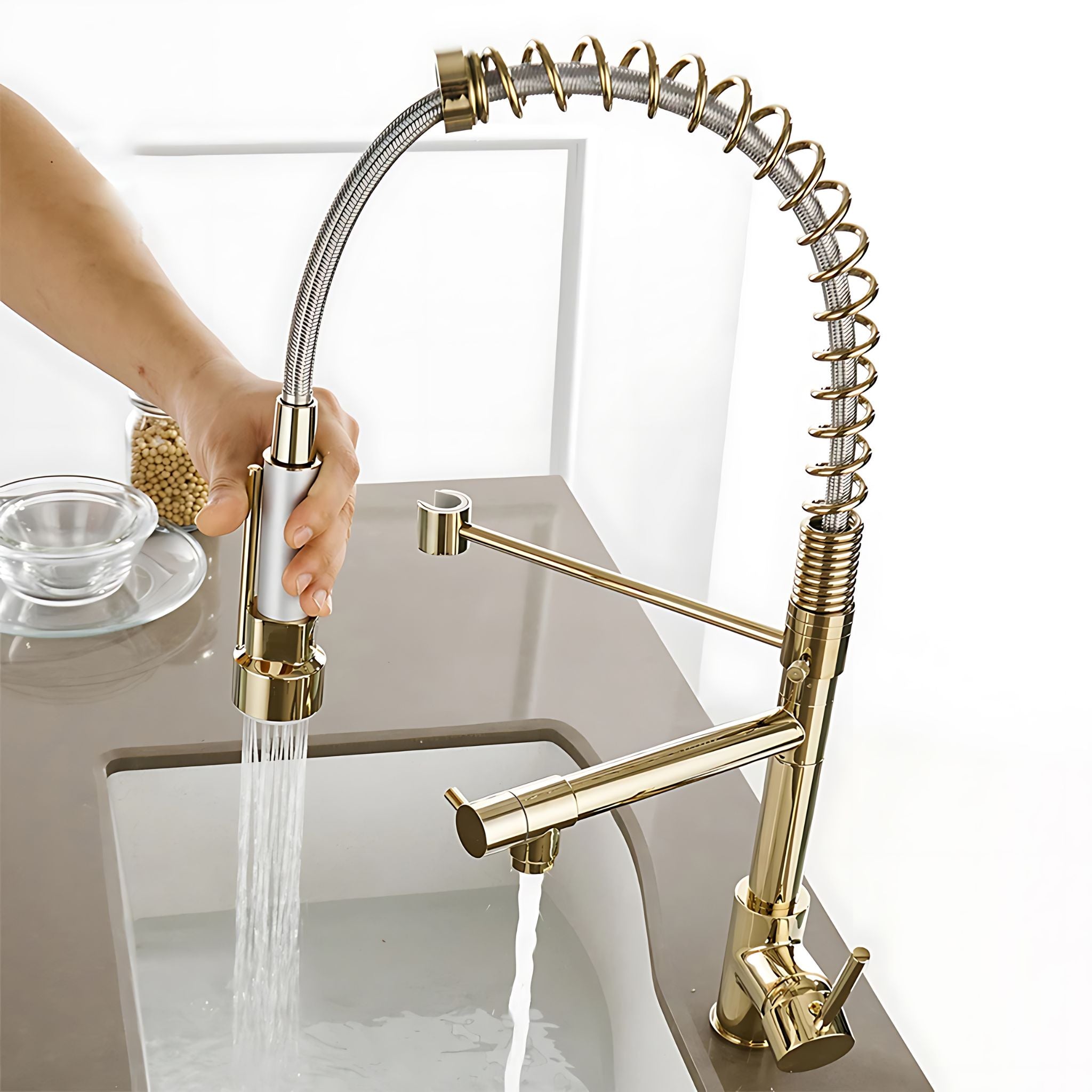 Gold pull-down kitchen faucet with spring hose pulled into sink for rinsing with active water flow #color_gold