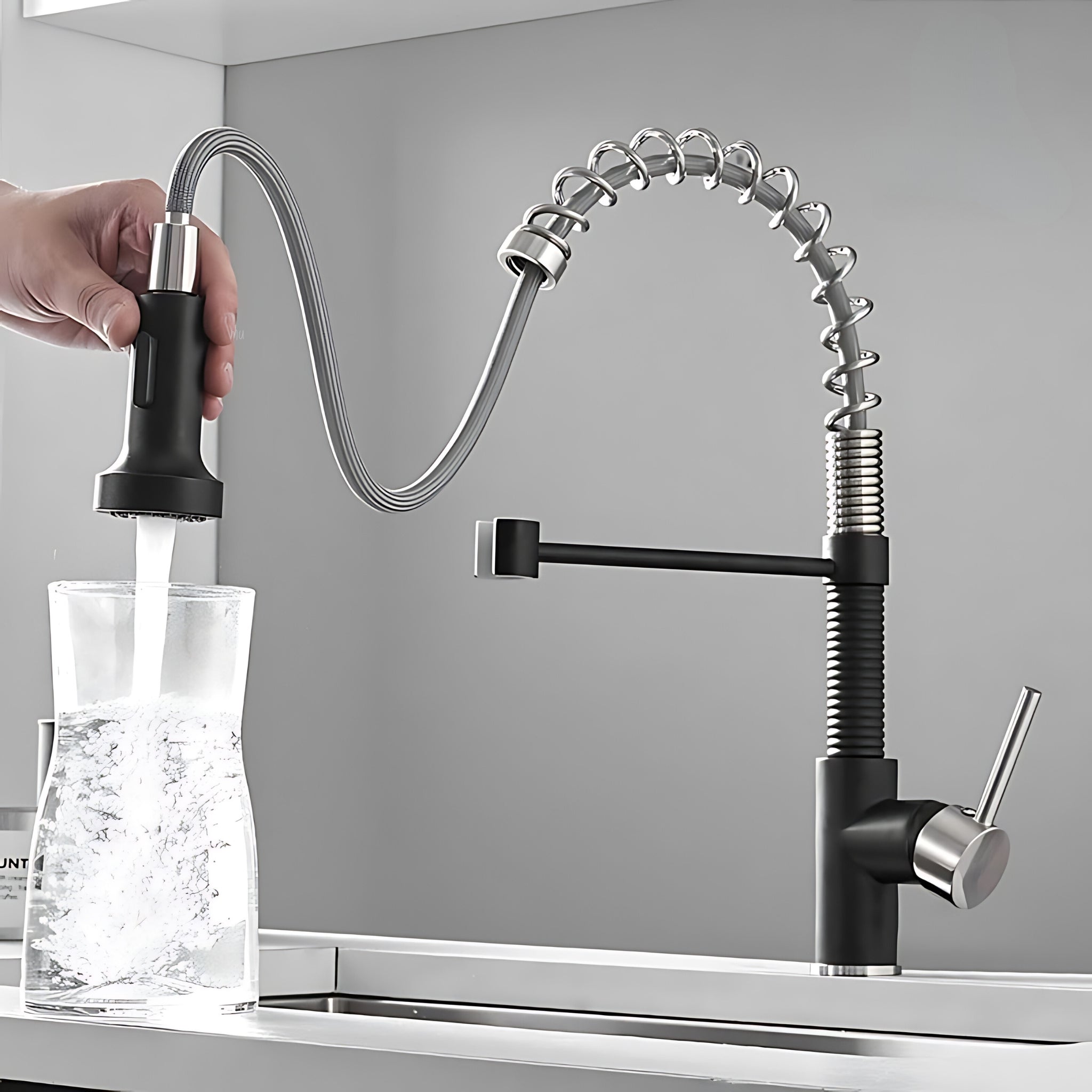 Spiro v2.0 matte black and brushed nickel kitchen faucet sprayer head held out on the hose, filling a glass in stream mode #color_matte black and brushed nickel